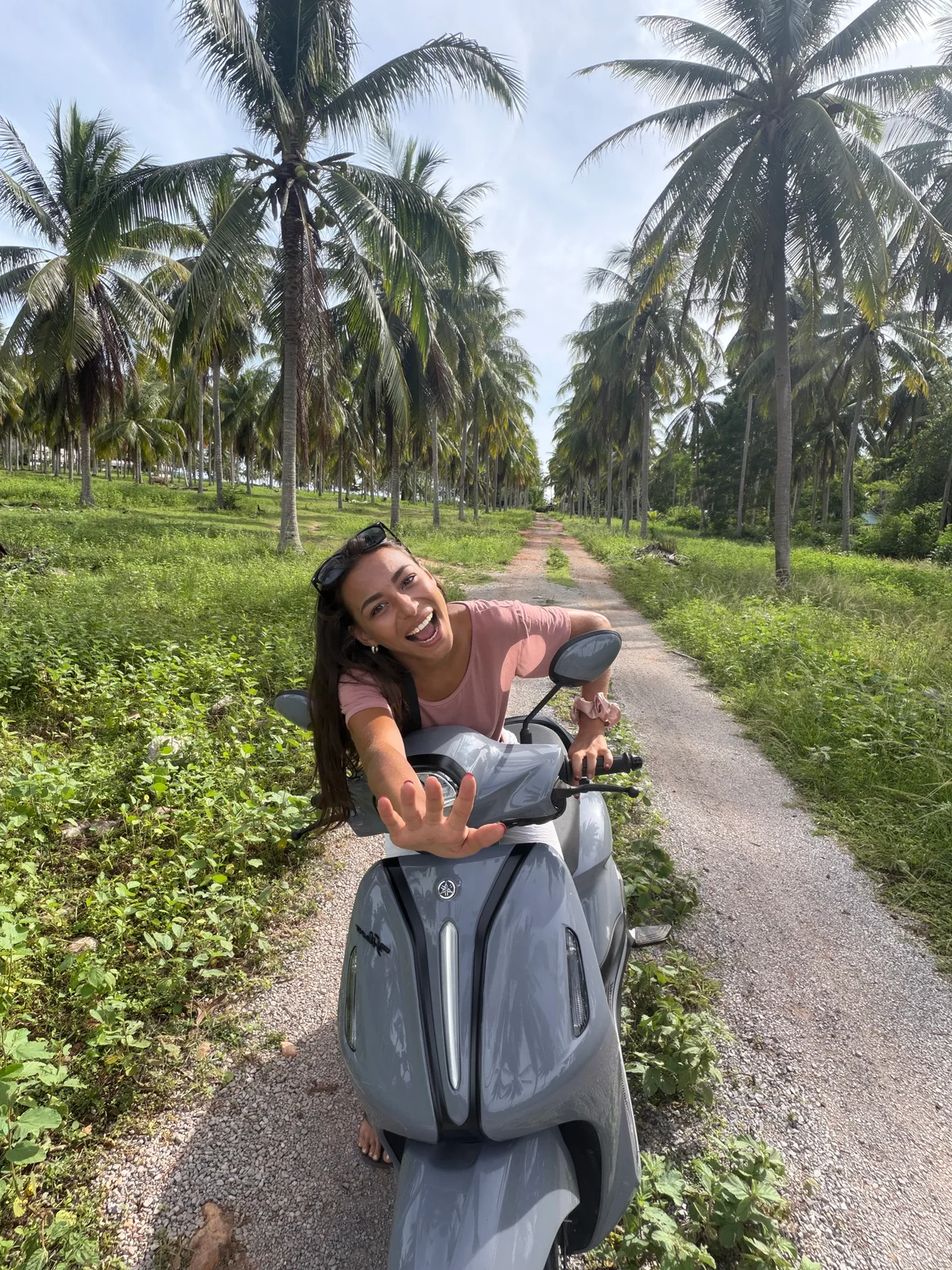 Leïla sur un scooter, au milieu des palmiers